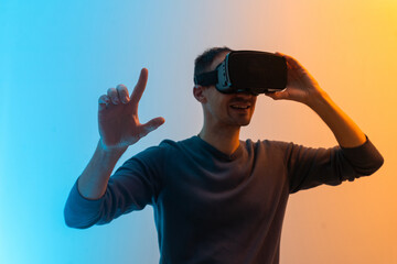 Fototapeta premium Virtual glasses gaming experience. Neon lighting. Young european man