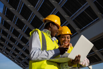 Female engineers using laptop on construction site with solar panels
