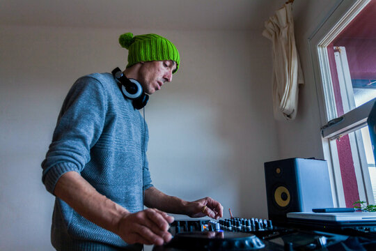 Man playing on DJ mixing console at home
