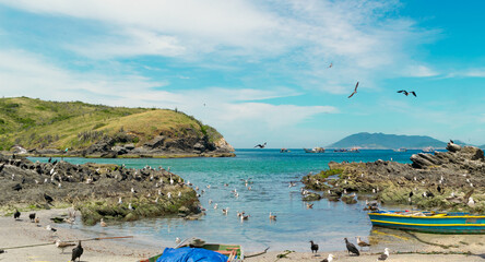 Praia do Forte São Mateus in Cabo Frio, with sea water around it, many fishing boats, beautiful sky with clouds and mountains in the background.