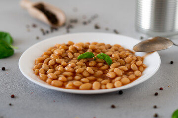 Baked Beans in tomato sauce in a plate against a grey background. Food. Food background. Close-up