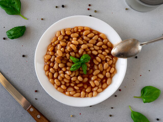 Baked Beans in tomato sauce in a plate against a grey background. Food. Food background. Top view