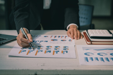 Accountant holding pen and using calculator doing company taxes on wooden table in office tax, accounting, statistics and analytical research concept, business finance