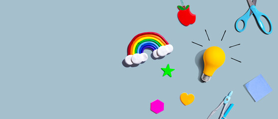 Fototapeta premium Idea light bulb with a rainbow and school supplies overhead view - flat lay