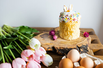 Easter cake, colorful eggs and tulips on wooden table, space for text