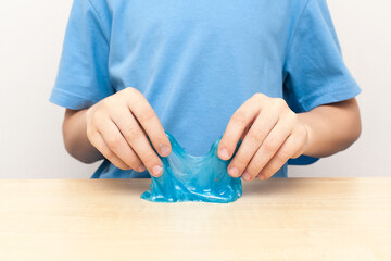 Child's hands playing with a purple slime with colored dots over a white background.