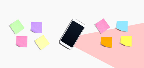 Smartphone with many colorful sticky notes - desk flat lay