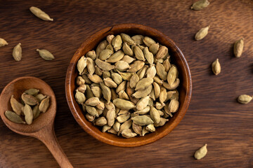 Cardamon seeds bowl. Cardamon seeds spread on wooden background. Up view shoot.