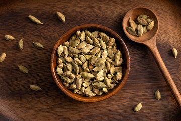 Cardamon seeds bowl. Cardamon seeds spread on wooden background. Up view shoot.