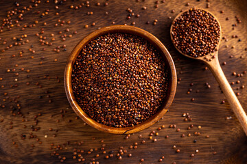 Uncooked red quinoa seeds wooden spoon. Quinoa seeds spread on rustic background. Up view degree shoot.