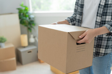 Moving house, relocation. Woman hand holding carton box on new apartment, inside the room was a cardboard box containing personal belongings and furniture. move in the house or condominium