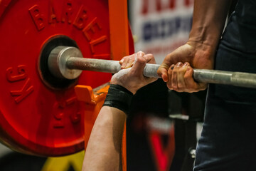 arm powerlifter in wrist wraps to hold heavy barbell before bench press powerlifting competition