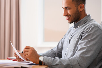 Fototapeta premium Happy businessman working with documents at wooden table in office