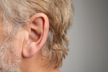 Closeup view of man against light grey background, focus on ear