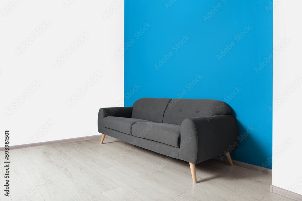 Wall mural Stylish grey sofa near blue wall in room. Interior design