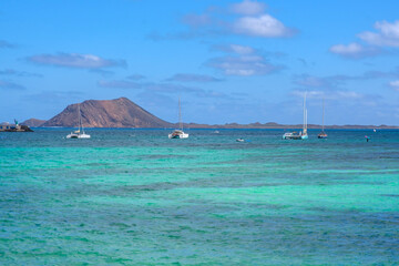 View on Corralejo beach, Lobos island, blue water and white sailboaits on the Canary Island Fuerteventura, Spain.