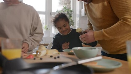 Father pouring syrup on pancake for son with Down syndrome