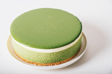 Layered matcha cheesecake on white plate. Gluten free no bake dessert. Healthy sweet food.