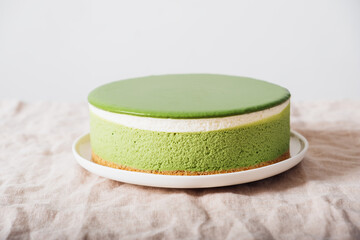 Layered matcha cheesecake on white plate. Gluten free no bake dessert. Healthy sweet food.