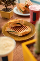 Split in half meat sandwich with ham and cheese in wooden table with drinks	