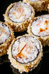 hot sushi roll tempura with eel shrimp crab salmon cream cheese cucumber avocado unagi on a black mirror background
