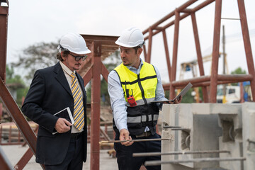 Businessman and male engineer discussing the quality of steel bar in concrete for making precast concrete wall at construction site.