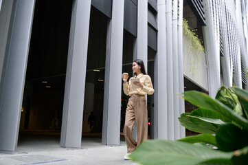 A young businesswoman is working in modern city downtown of Singapore - obrazy, fototapety, plakaty