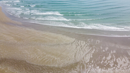 Wet coastal sand and sea waves, top view. Sandy beach and ocean tide. Seascape. Aerial view of waves
