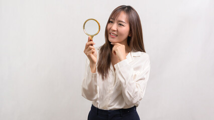 Young asian businesswoman holding magnifying glass over white background, analysis and finance concept