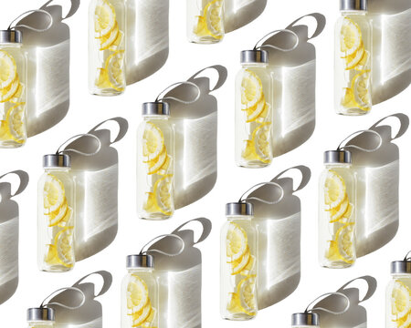 Trend pattern with glass bottle with lemon water drink detox at sunlight on white background. Top view stylish glass reusable water bottle with yellow sliced lemon, with hard shadow and caustic