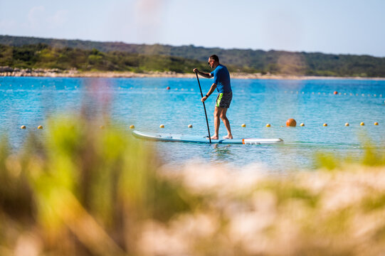 Man riding SUP stand up paddle on vacation.
