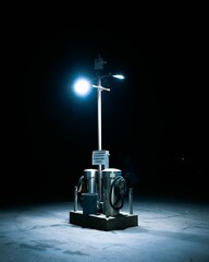 Vertical shot of two steel trash cans with a light stand and a warning to not dump household garbage