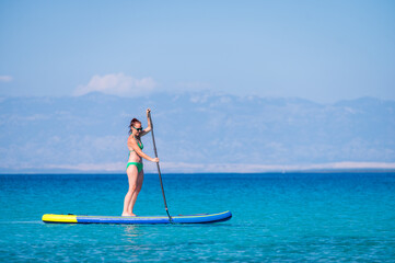 Woman riding SUP stand up paddle on vacation.