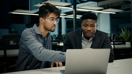 Businessman african man lawyer mentor help male indian client with computer work consult customer explain online business software services ethnic men colleagues look at laptop screen office meeting