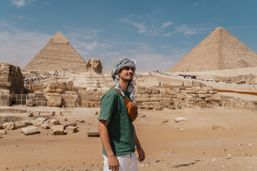 young man in a turban with great sphinx of Giza and pyramids in the background. El Cairo. Egypt