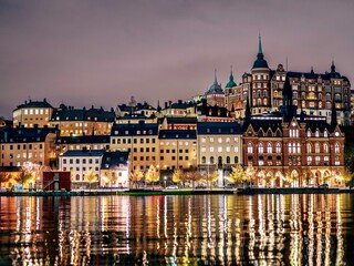 Buildings line the shore of a tranquil body of water in the evening in Stockholm, Sweden