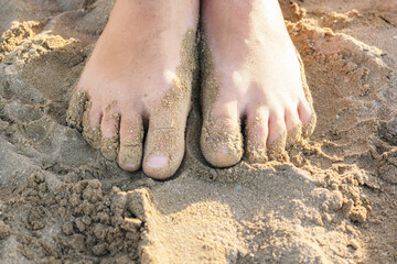Close-up feet of child in the sand on a sandy beach. Top view, flat lay. Vacation concept.