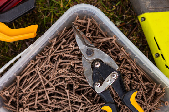 a bucket full of bolts and pliers on grass in the field