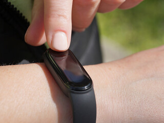 Using a fitness bracelet, a woman measures her pulse on the display of a fitness bracelet