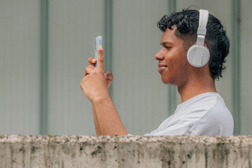 young male with headphones and mobile phone in the street