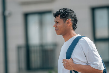 young latino man with backpack in the street