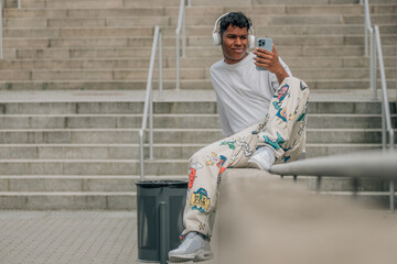 young latin male with headphones and mobile phone in the street