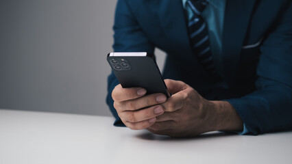 Close up view of young professional businessman using smartphone while sitting at his office desk.