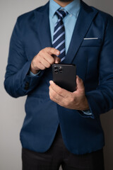 Close up view of young professional businessman using smartphone while standing in his office room.