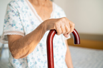 Obraz premium Asian elderly disability woman holding waling stick, wood cane, round handle, walking aid for help to walk.