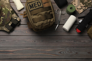 Military first aid kit on wooden table, flat lay. Space for text