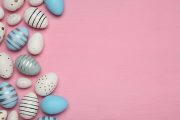 Fototapeta na wymiar Flat lay composition with festively decorated Easter eggs on pink wooden table. Space for text