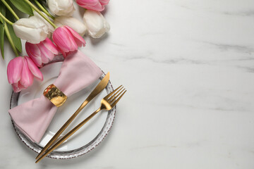 Fototapeta na wymiar Stylish table setting with cutlery and tulips on white marble background, flat lay. Space for text