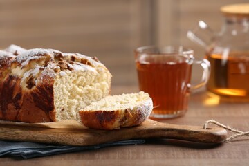 Fototapeta na wymiar Delicious yeast dough cake and tea on wooden table, closeup