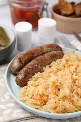 Plate with sauerkraut and sausages on table, closeup